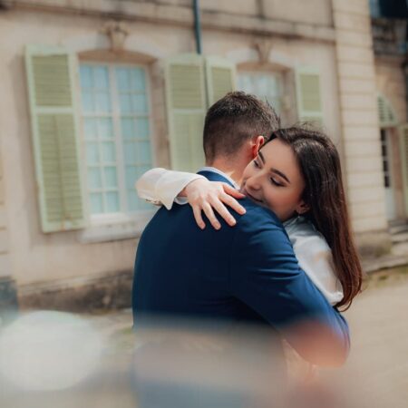 Couple s'enlaçant devant un bâtiment ancien.