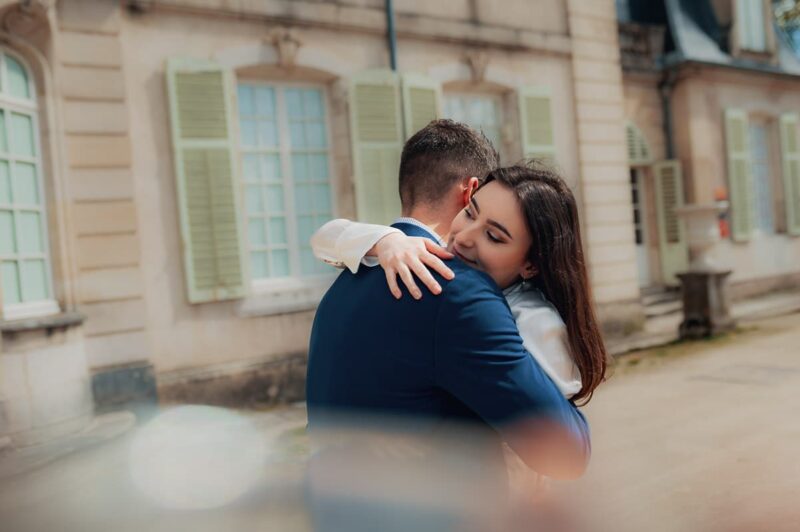 Couple s'enlaçant devant un bâtiment ancien.