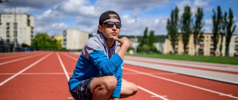 Personne assise sur piste d'athlétisme en plein air.