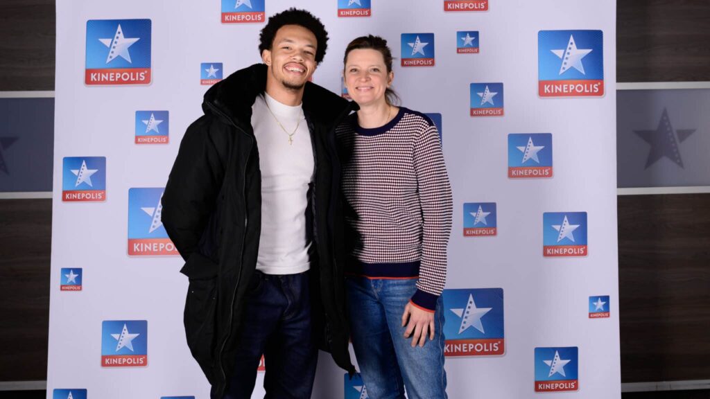 Deux personnes souriant devant logo Kinepolis.