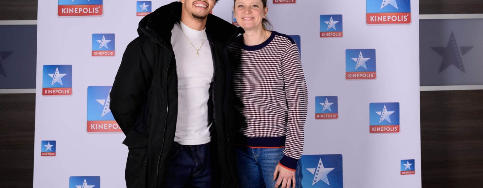 Deux personnes souriant devant logo Kinepolis.