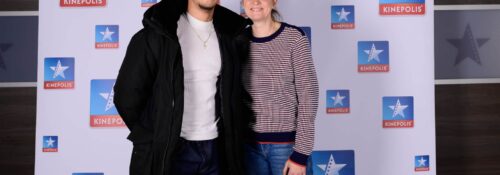 Deux personnes souriant devant logo Kinepolis.