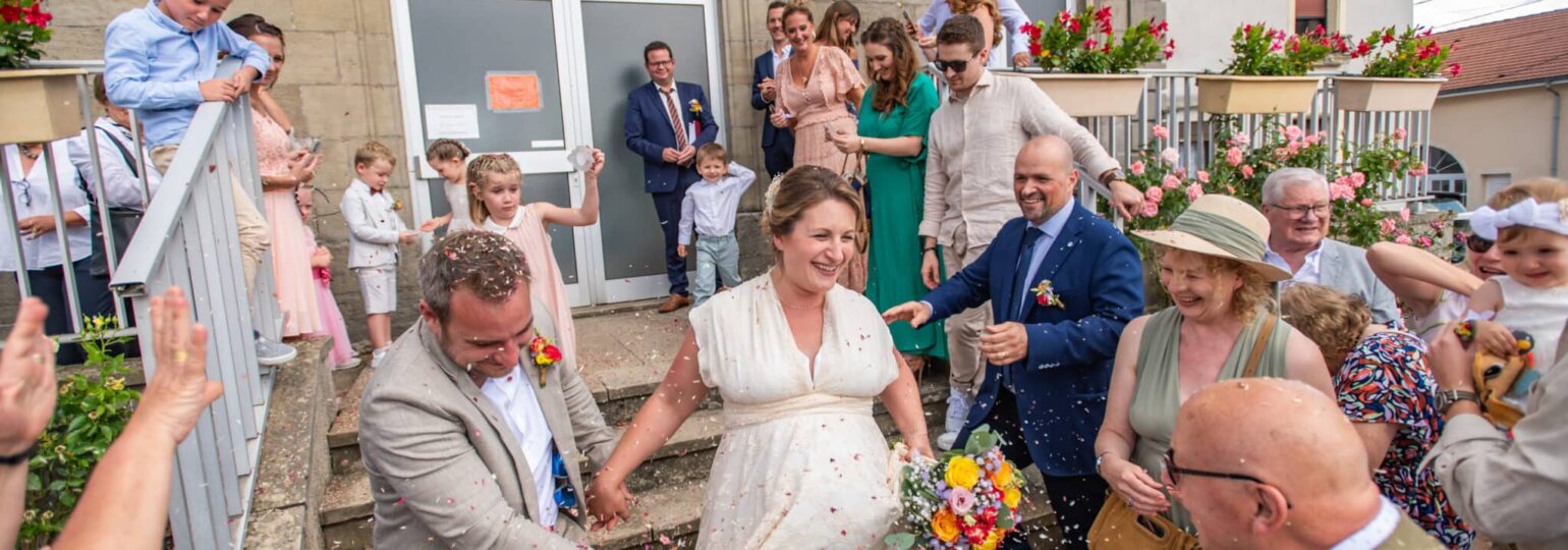 Sortie de mariage des mariés sous pluie de confettis.