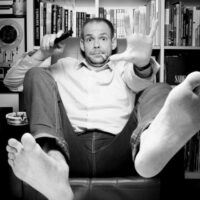 Homme assis avec les pieds en avant, télécommande.