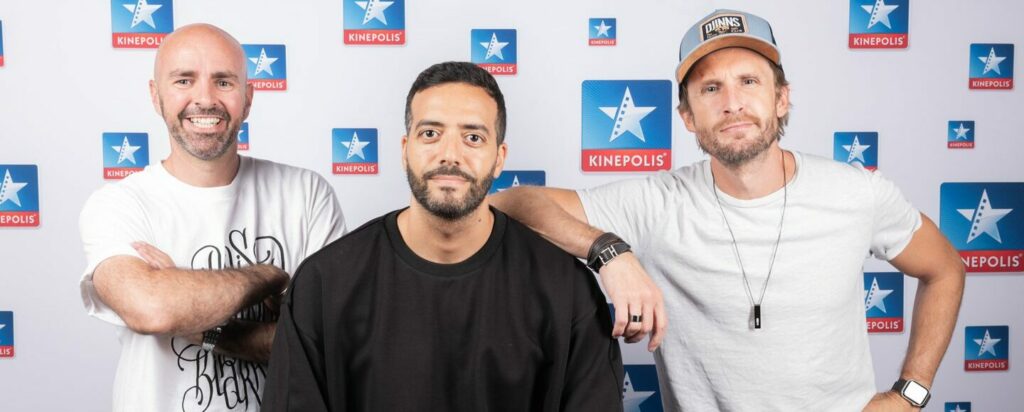 Trois hommes devant un fond Kinepolis.