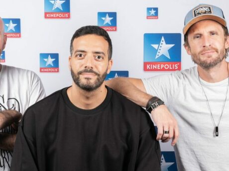 Trois hommes devant un fond Kinepolis.