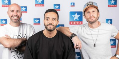 Trois hommes devant un fond Kinepolis.