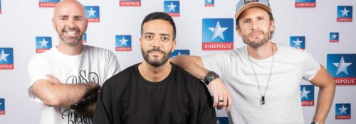 Trois hommes devant un fond Kinepolis.