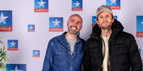 Deux personnes posent devant un logo Kinepolis.