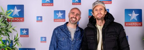 Deux personnes posent devant un logo Kinepolis.