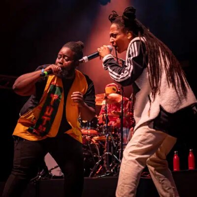 Deux artistes chantent sur scène avec des micros.