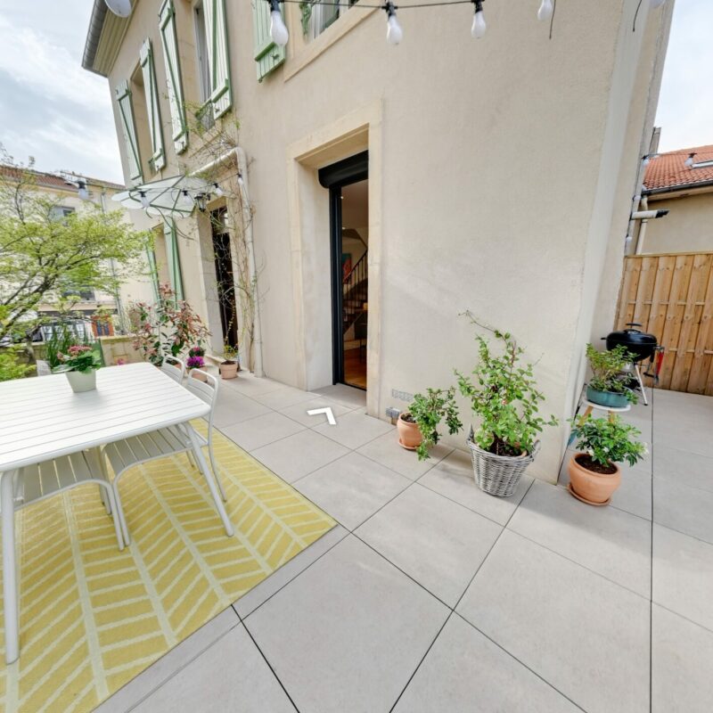 Terrasse avec table et plantes en pot.