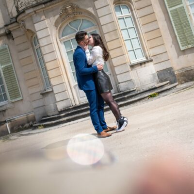 Couple s'embrassant devant un bâtiment historique.