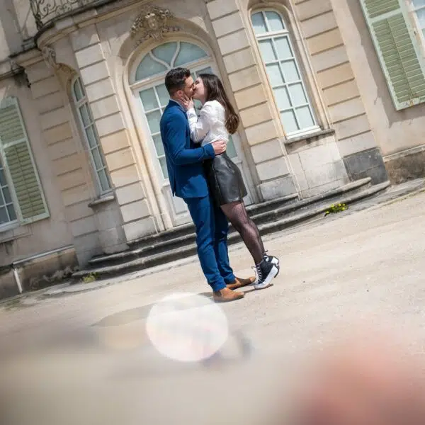 Couple s'embrassant devant un bâtiment ancien.