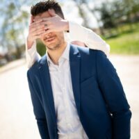 Personne voilant les yeux d'un homme en veste.