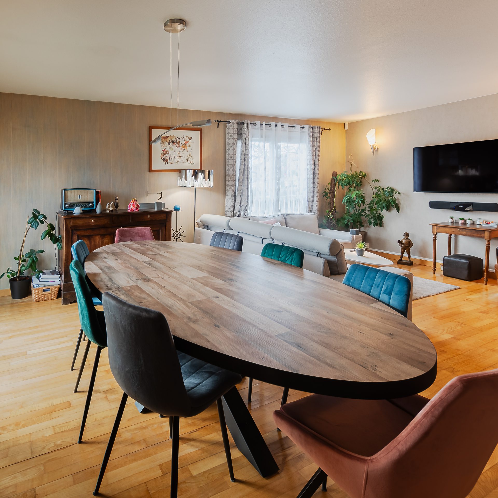 Salon moderne avec table ovale et fauteuils colorés.