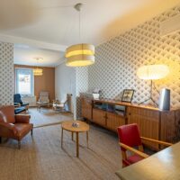 Salon rétro avec mobilier vintage et papier peint texturé.