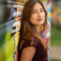Femme posant devant un mur coloré.