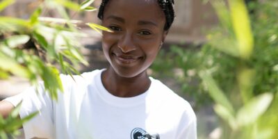 Femme souriante en t-shirt blanc parmi les plantes.