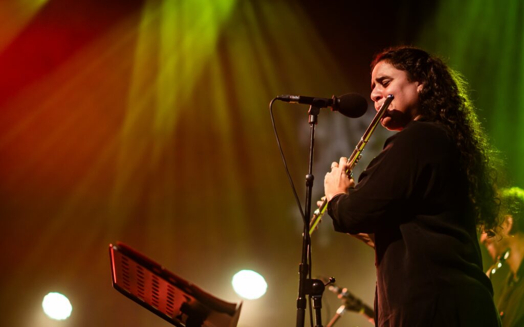 Musicienne jouant de la flûte sur scène éclairée.