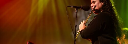 Musicienne jouant de la flûte sur scène éclairée.