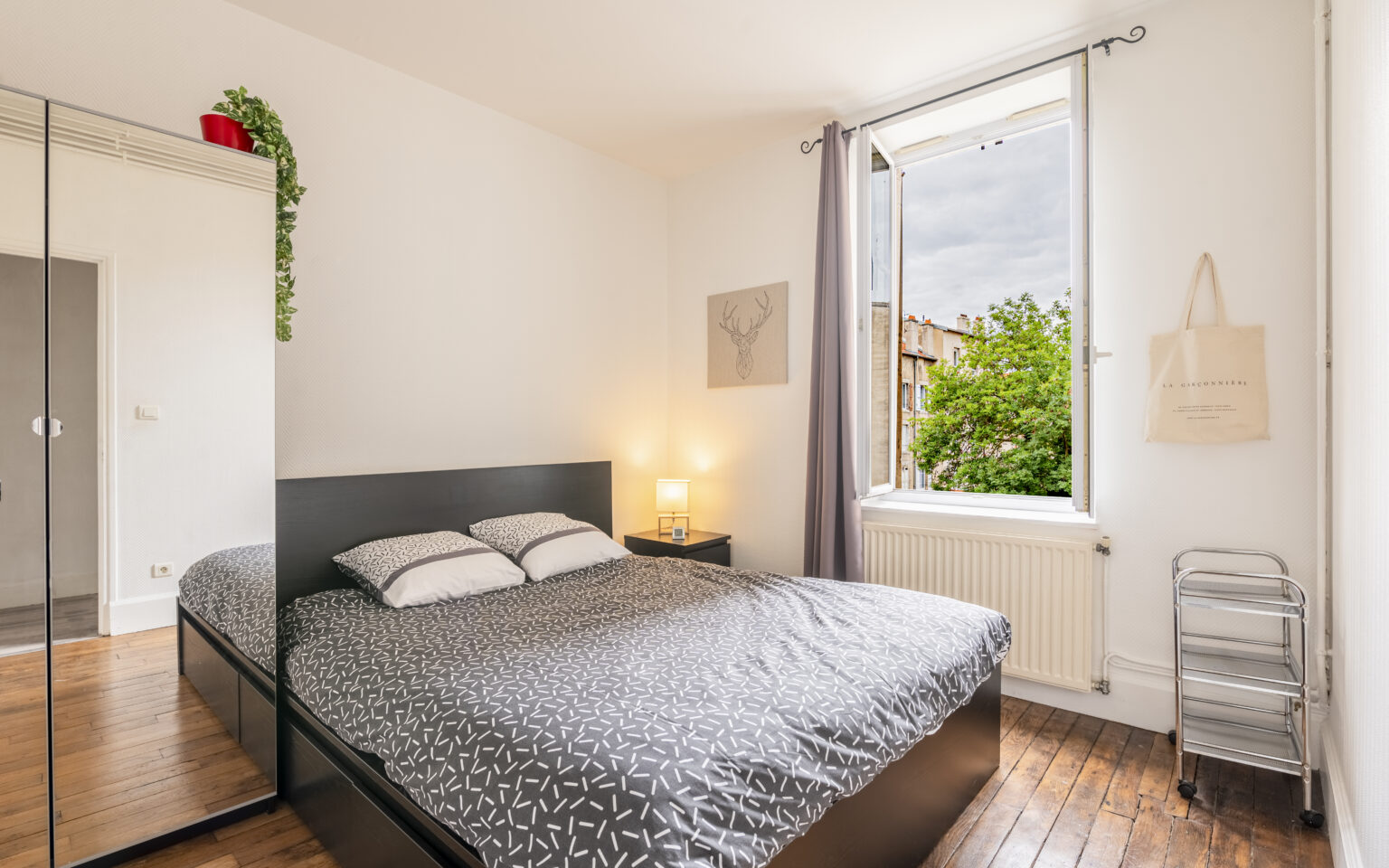 Chambre avec lit double, fenêtre ouverte, armoire miroir.