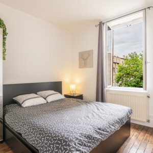 Chambre avec lit double, fenêtre ouverte, armoire miroir.