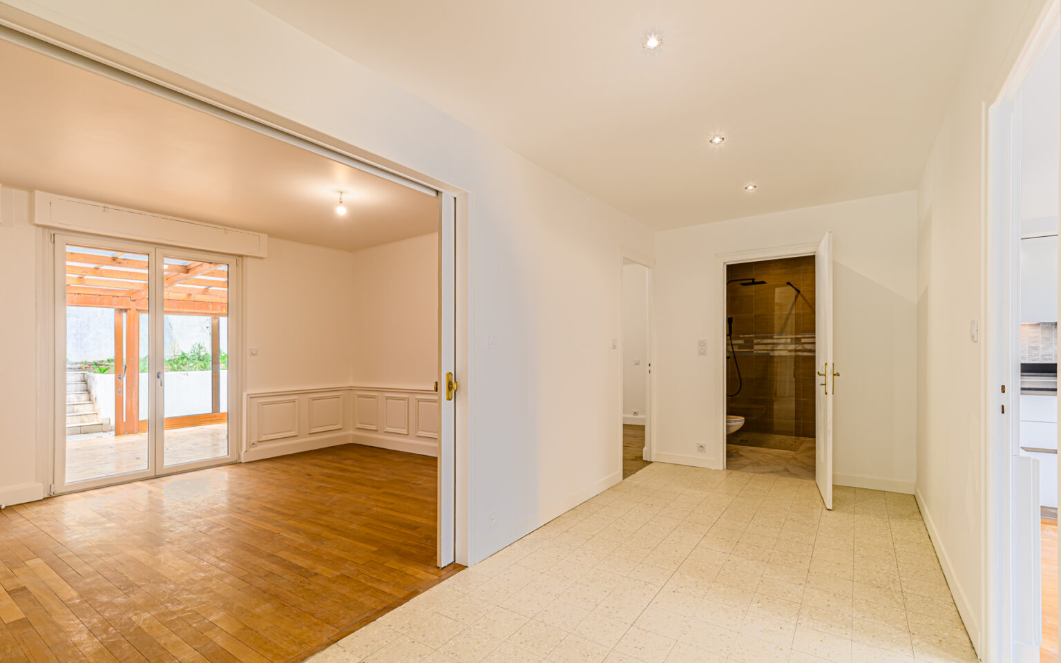 Salon lumineux avec parquet et terrasse.