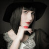 Femme avec chapeau noir, rouge à lèvres vif.