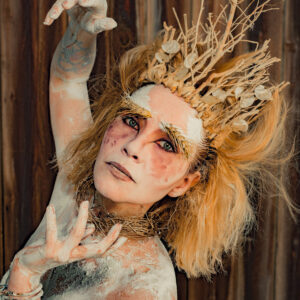 Personne maquillée avec une couronne de branches.