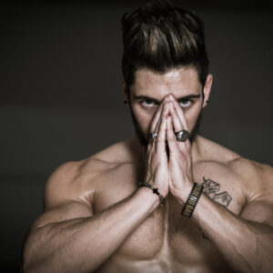 Homme musclé concentré mains jointes devant visage.
