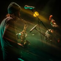 Musicien jouant du saxophone sur scène, ambiance lumineuse.