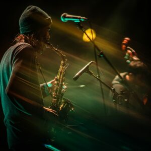 Musicien jouant du saxophone sur scène, ambiance lumineuse.