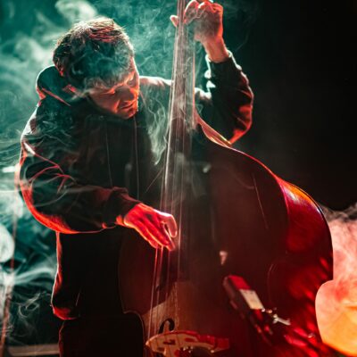 Musicien jouant de la contrebasse sur scène avec fumée.