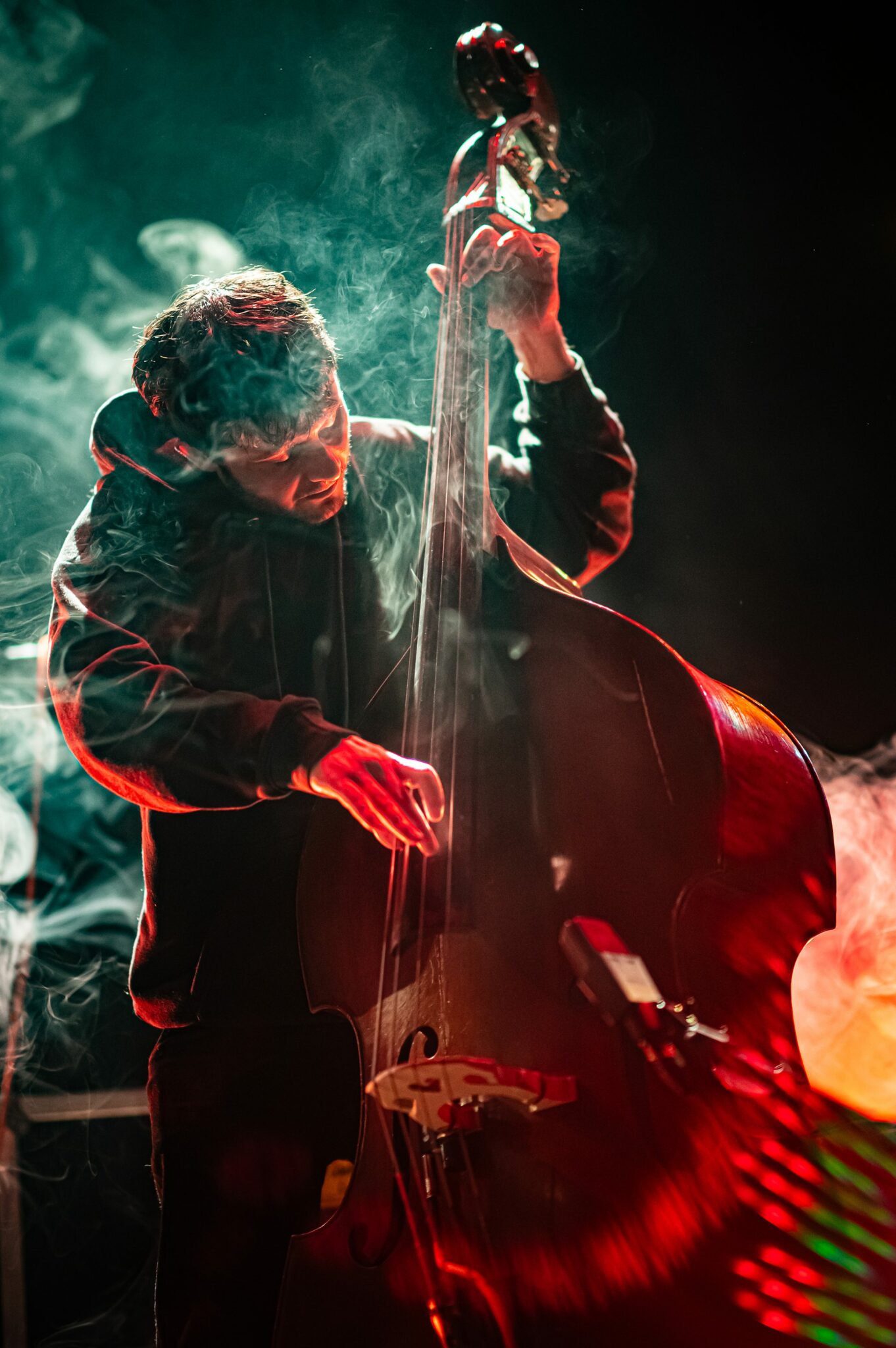 Musicien jouant de la contrebasse sur scène avec fumée.