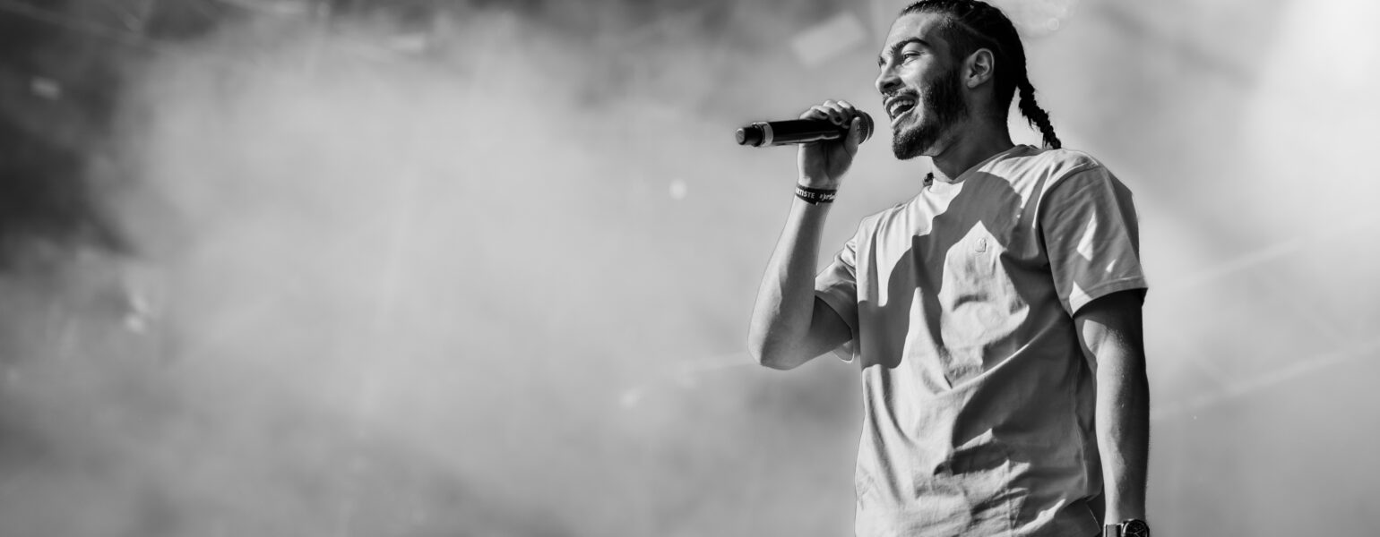 Chanteur sur scène, microphone en main.