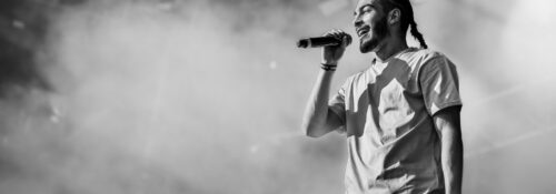 Chanteur sur scène, microphone en main.