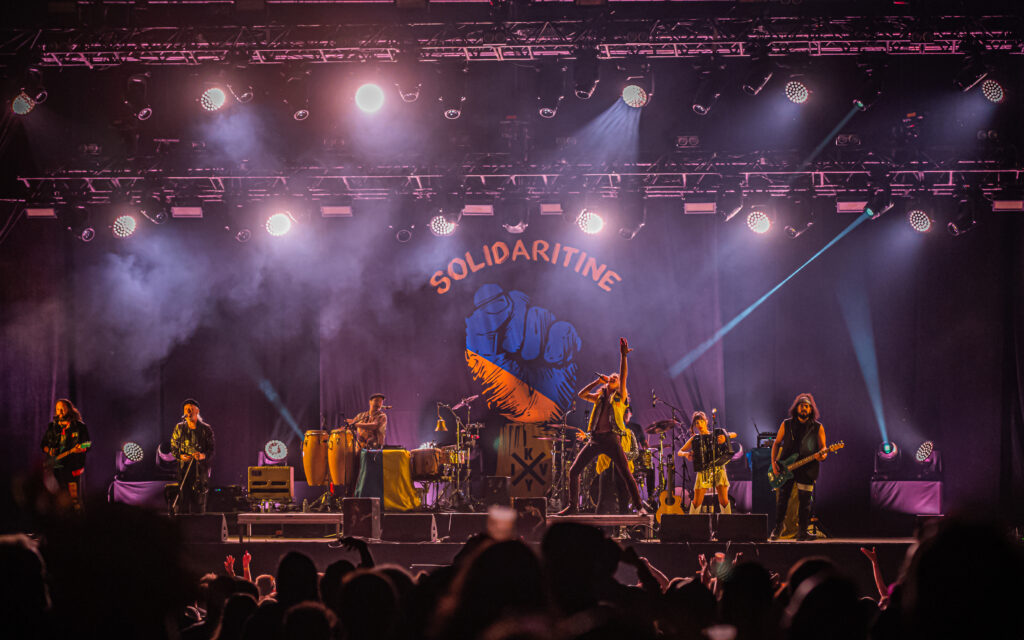 Concert avec éclairage coloré et décor 'Solidaritine'.