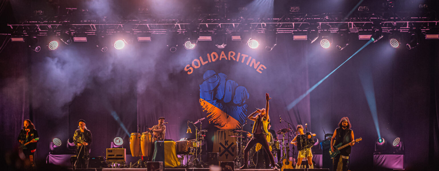 Concert avec éclairage coloré et décor 'Solidaritine'.