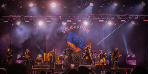 Concert avec éclairage coloré et décor 'Solidaritine'.