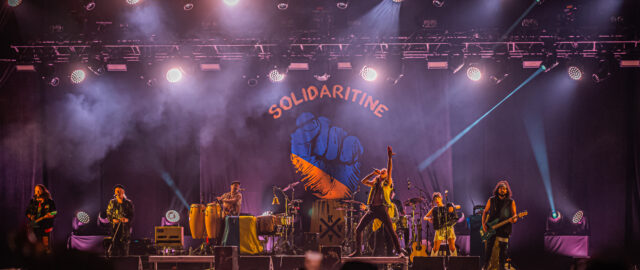 Concert avec éclairage coloré et décor 'Solidaritine'.