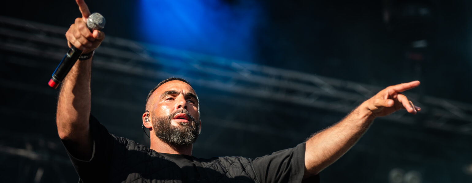 Chanteur en concert, lumières vives sur scène.