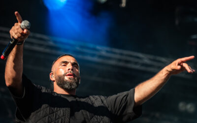 Chanteur en concert, lumières vives sur scène.