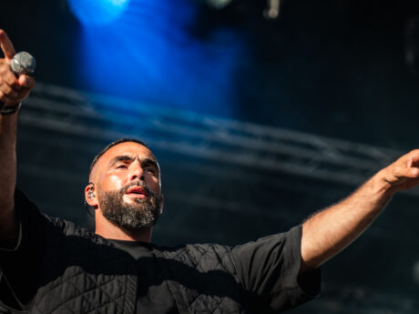 Chanteur en concert, lumières vives sur scène.