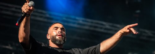 Chanteur en concert, lumières vives sur scène.