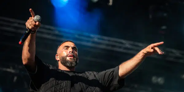 Chanteur en concert, lumières vives sur scène.