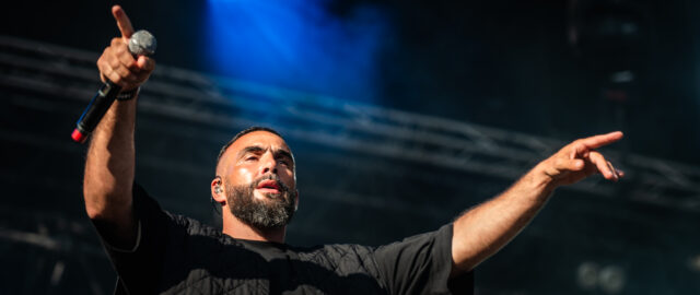 Chanteur en concert, lumières vives sur scène.