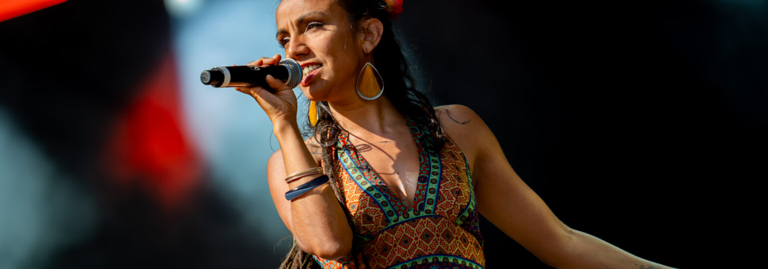 Chanteuse sur scène avec micro et robe colorée.