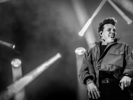 Chanteur souriant sur scène en concert noir et blanc.