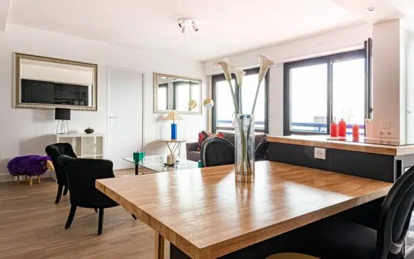 Salon moderne avec table en bois et fauteuils noirs.